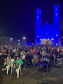 Pessoas assistindo cinema em uma praça com uma igreja ao fundo
