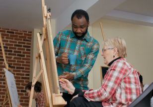 Homem ensina senhora a pintar