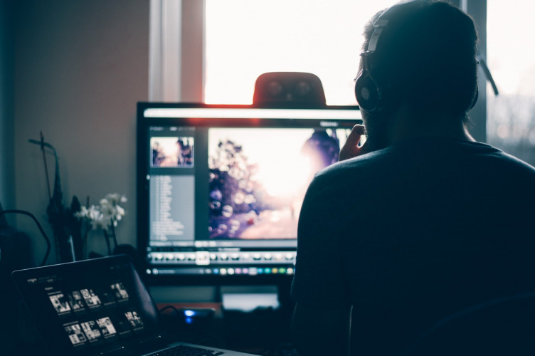 Homem editando conteúdo em seu computador em casa