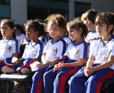 Crianças sentadas vestidas com o uniforme da escola