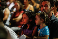 Duas meninas juntas a um adulto, comendo pipoca.