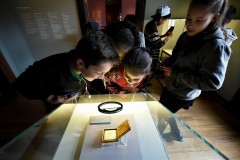 Crianças observam daguerreótipo com foto rara de Iria Corrêa na exposição "Em foco: Iria Corrêa".