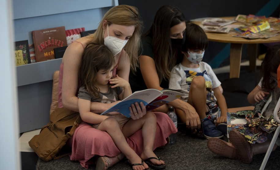 Mulher lê com criança no colo na FLIB