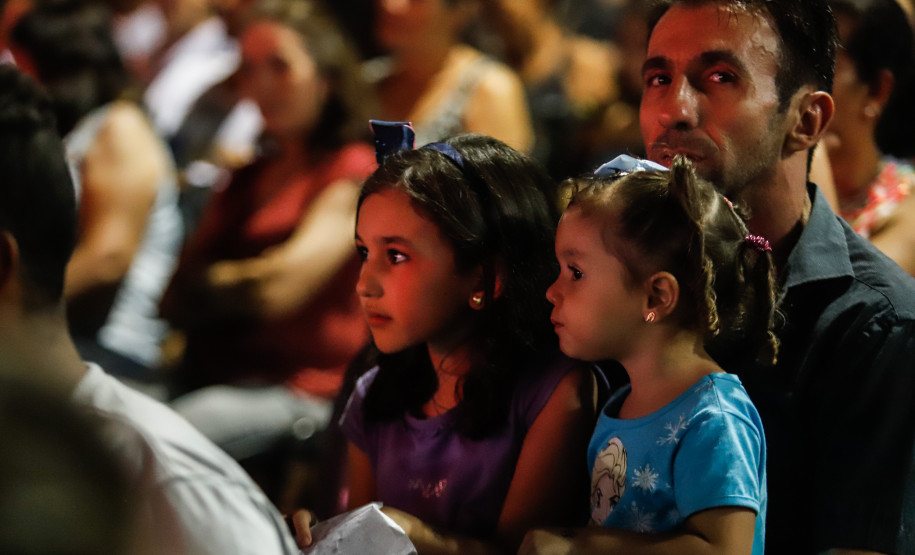 Duas meninas juntas a um adulto, comendo pipoca.