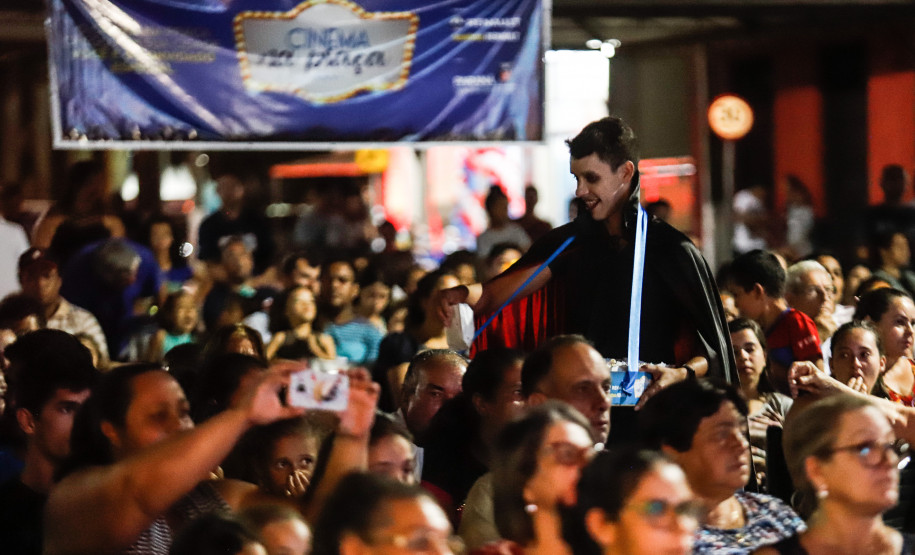 Homem vestido de Drácula entregando pipoca para as pessoas