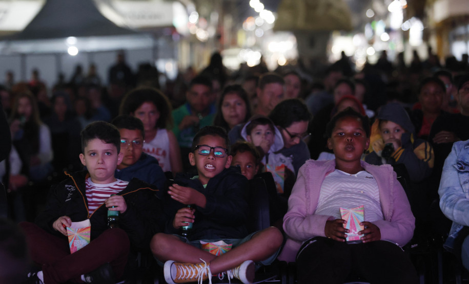 Crianças assistindo cinema em uma praça