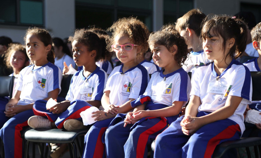 Crianças sentadas vestidas com o uniforme da escola