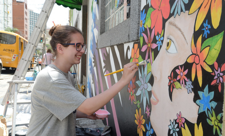 Aluna do CJAP pinta mural com base em projeto feito em sala de aula.