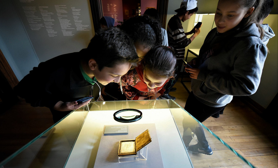 Crianças observam daguerreótipo com foto rara de Iria Corrêa na exposição "Em foco: Iria Corrêa".